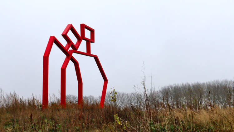 Kunstwerk van rode metalen latten uitbeeldend twee personen.